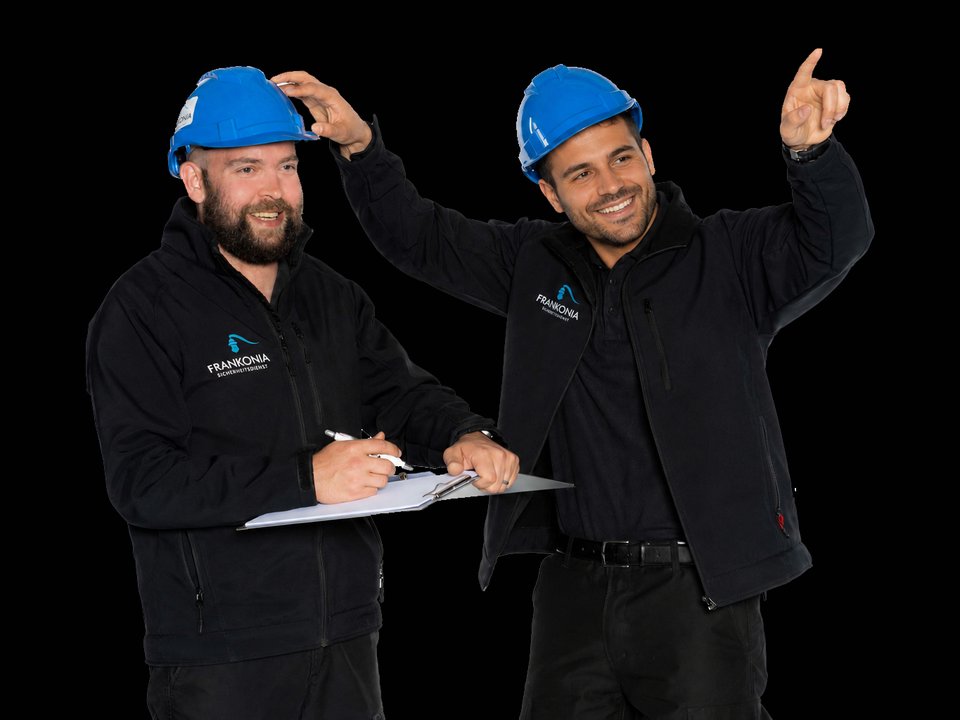 Zwei FRANKONIA Mitarbeiter mit Schutzhelm und Checkliste an einem Objekt